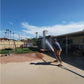 Man using FireFighter1 fire hose to spray water in backyard, showcasing heavy duty hose from Wholesale Pool Mart (WPM).