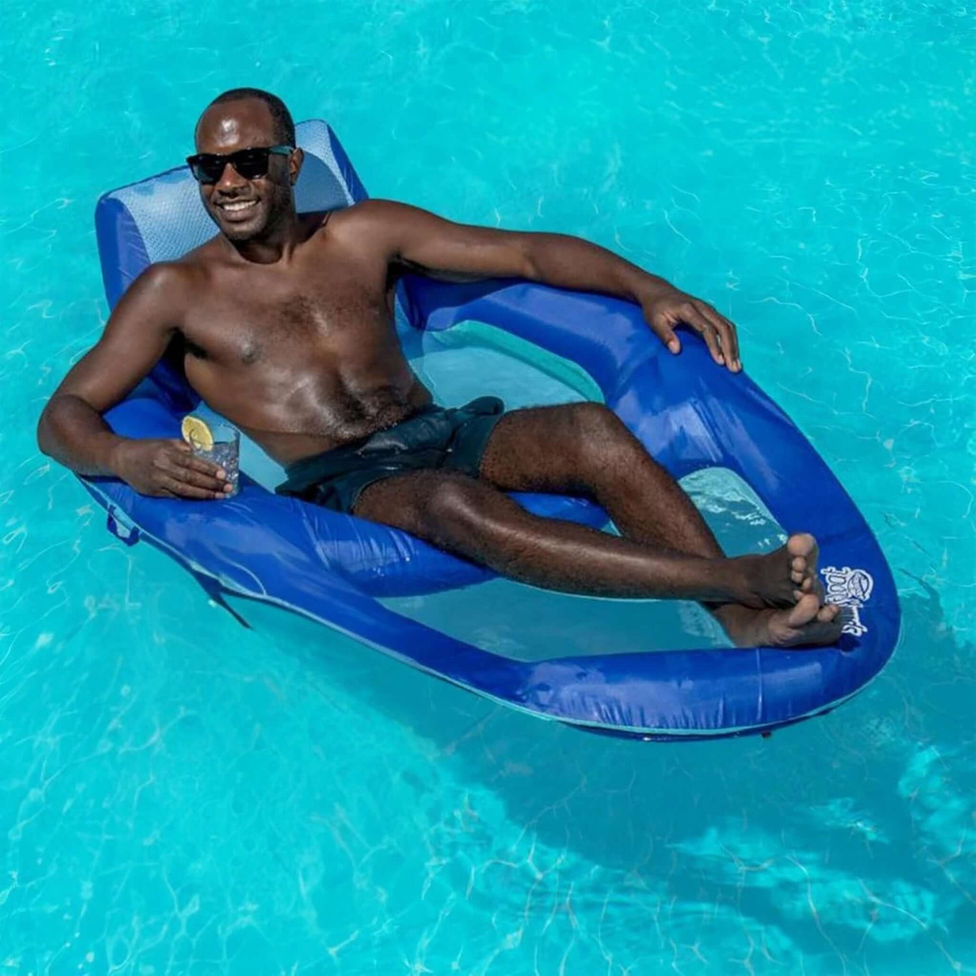 Adult man relaxing on a SwimWays Spring Float Recliner XL in a pool, enjoying leisure time, SKU 6069706, Wholesale Pool Mart WPM.
